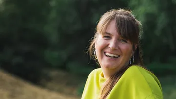 Lächelnde Frau im Freien in grüner Natur.