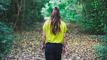 Woman walking through a forest path.