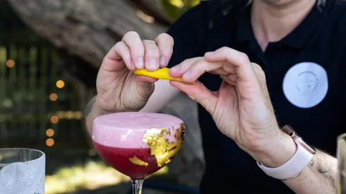 Hände garnieren Cocktail mit Zitrone im Freien.