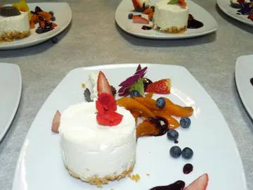 Cheesecake is presented on a plate with fruit.