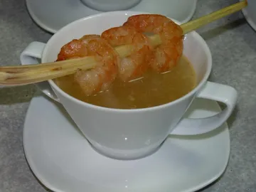 Schüssel mit Brühe, garnierte Garnelen auf einem Spieß.
