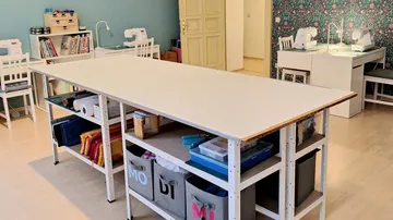 Großer Tisch im Nähzimmer mit Maschinen.