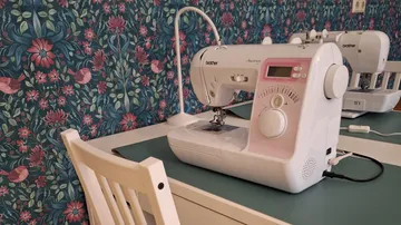 Nähmaschine auf Tisch mit Blumenmuster.