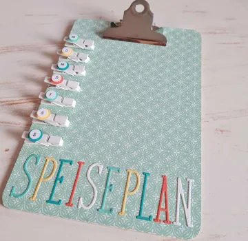 Klemmbrett mit Speiseplan in Pastellumgebung.