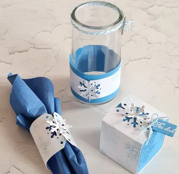 Glass jar with snowflake decor on table.