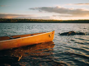 Kanu schwimmt im ruhigen Wasser bei Sonnenuntergang.