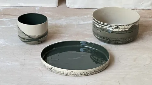 Ceramic pots and plate on wooden surface.