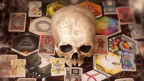 Schädel von Tarotkarten auf Tisch umgeben.