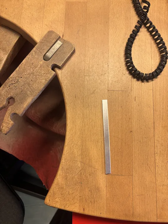 Wooden workbench with metal tool and cable.