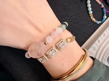 Wrist with multiple bracelets, dark surface.
