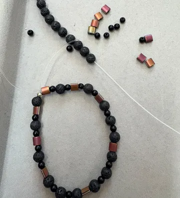 Beaded bracelet being assembled on grey surface.