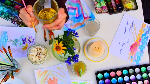 Hands painting on a colorful art desk.