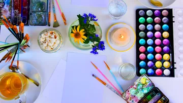 Art supplies and tea on a desk.