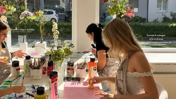 Personen malen an einem Atelier-Tisch.