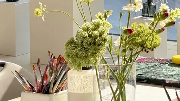 Pinsel und Blumen auf einem Tisch.