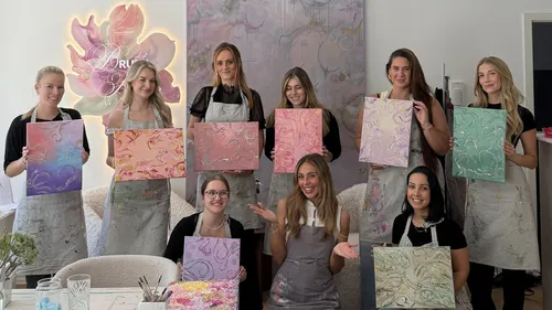 Group of women holding abstract paintings indoors.