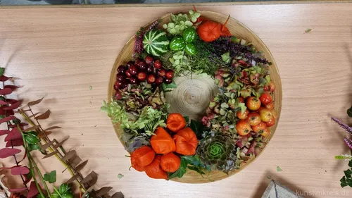 Decorative wreath with fruits on a wooden table.