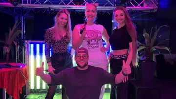Four people posing on stage, colorful lights.