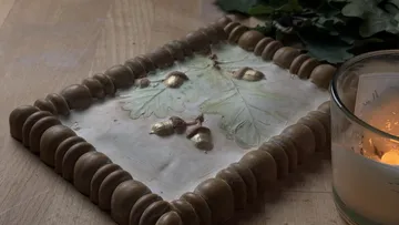 Frame with oak leaves on wooden table.