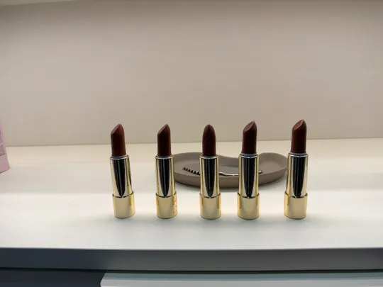 Five lipsticks displayed on a shelf.