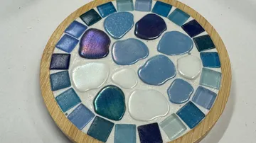 Bunter Mosaik-Untersetzer auf weißer Fläche.