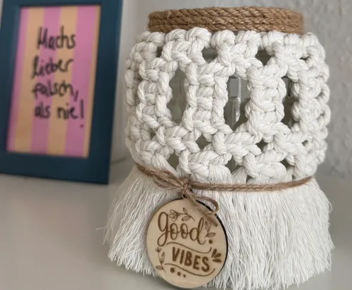 Macrame jar with 'Good Vibes' tag on table.