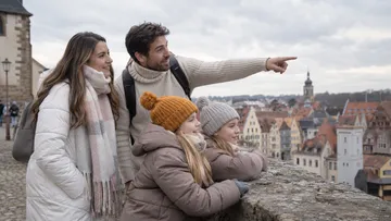 Family pointing city view from wall.
