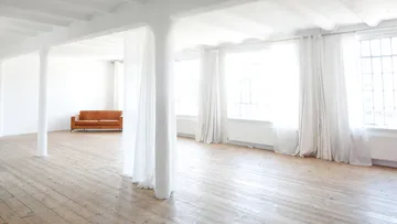 Sofa in sonnendurchflutetem, geräumigen Raum mit Fenstern.