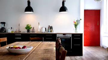 Küche mit Holztisch und roter Tür.