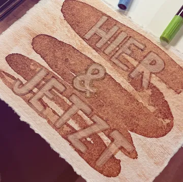 Paper with 'HIER & JETZT' in bold letters.