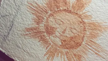 Sun sketch on textured white paper.