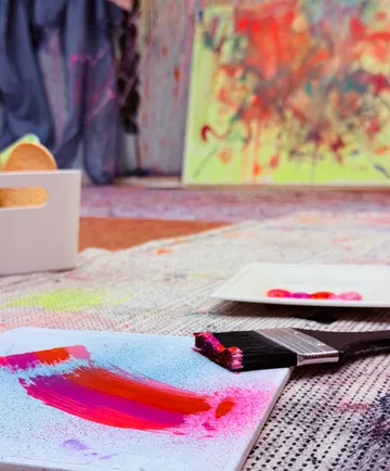 Paintbrush with colors on canvas in studio.
