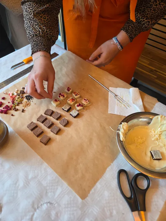 Person dekoriert Pralinen mit Belägen auf Pergament.