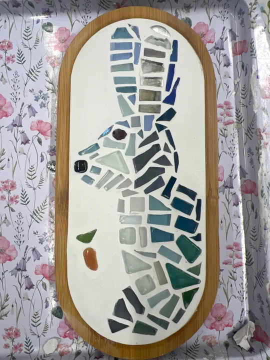 Mosaic fish design on wooden board.