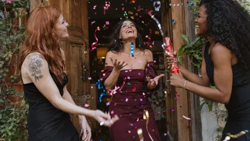 Frauen feiern mit Konfetti draußen.