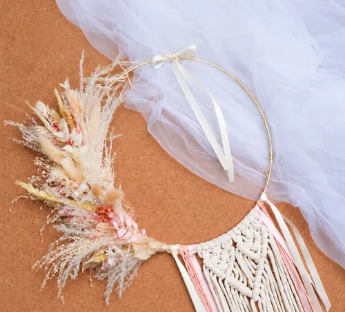 Dreamcatcher with dried flowers on fabric background.