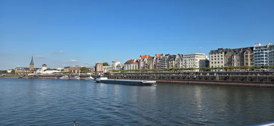 River with boat and city skyline, daytime.