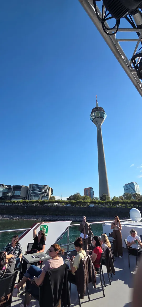 People seated on boat, tower in background.