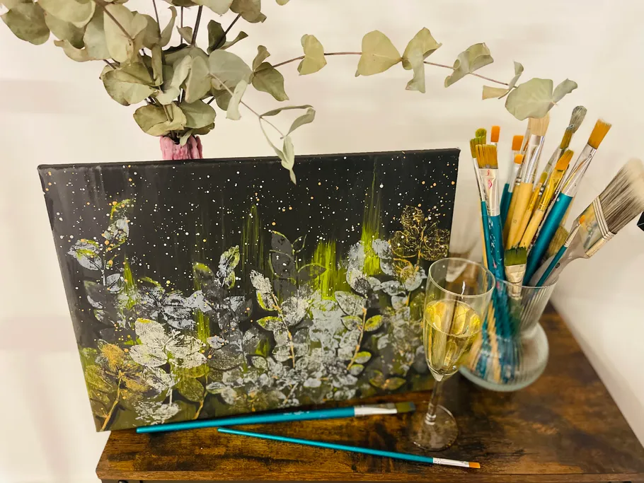 The painting is on a table, surrounded by painting utensils.