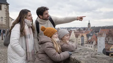 Family enjoys city view from stone wall.