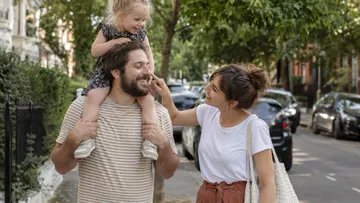 Familie spaziert und lächelt auf grüner Straße.