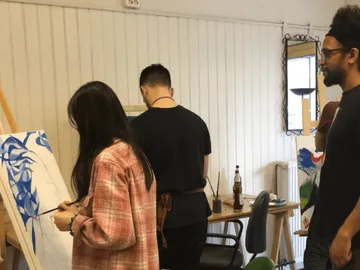 Artists paint with canvases in a bright studio.