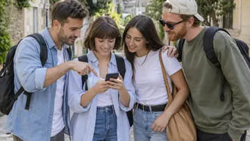 Group of friends looking at smartphone outdoors.