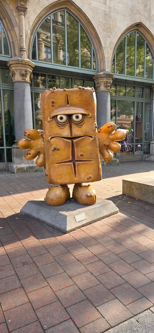 Lebkuchenfigur steht vor einem Gebäude.