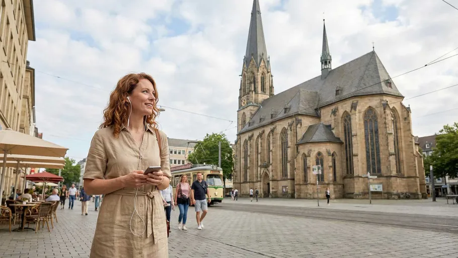 Frau geht mit Handy nahe historischer Kirche.