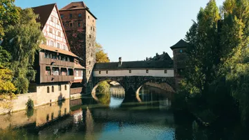 Medieval buildings reflect in a river.