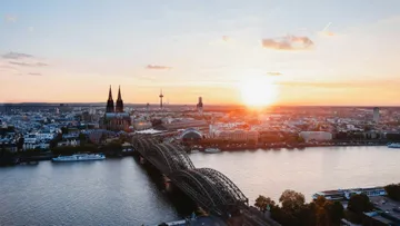 Sunset over Cologne skyline with river view.