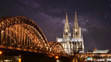 Bridge and cathedral under starry night sky.