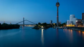 City skyline with river and tower at night.