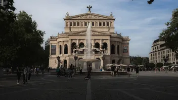 Historisches Opernhaus mit Brunnen auf Platz.